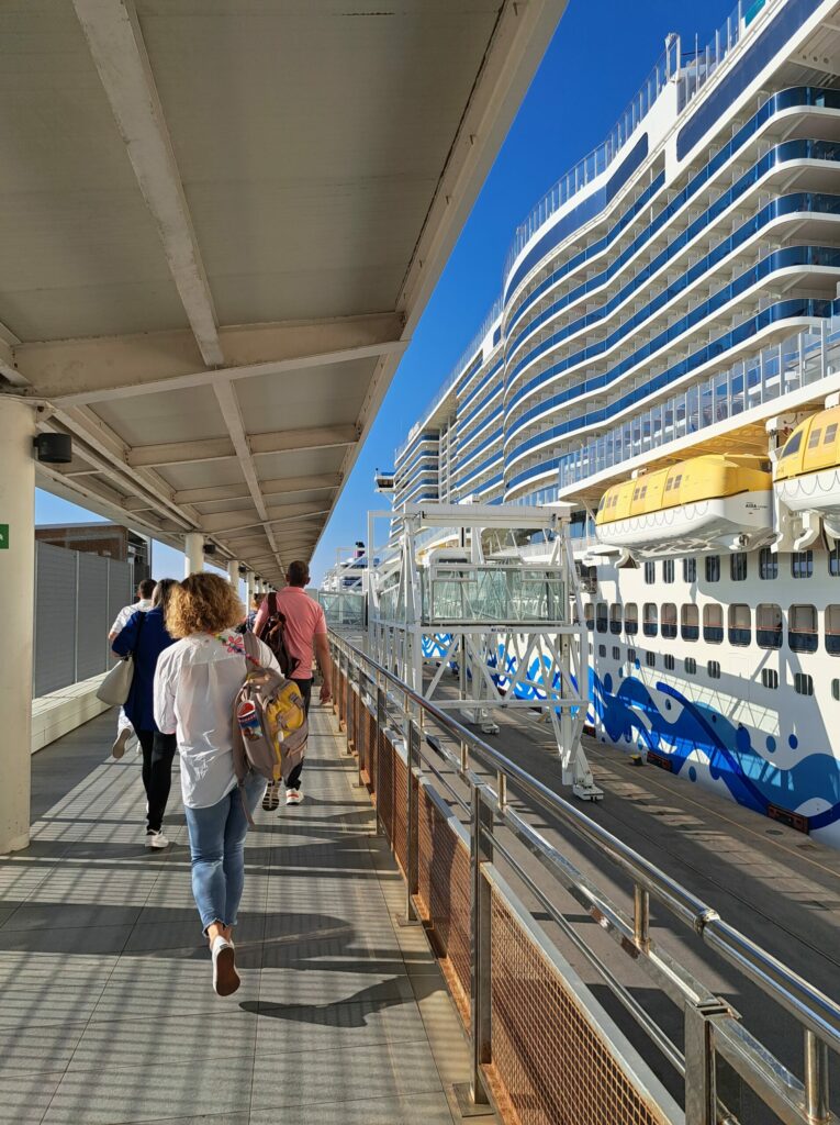 people walking on a walkway next to a large cruise ship