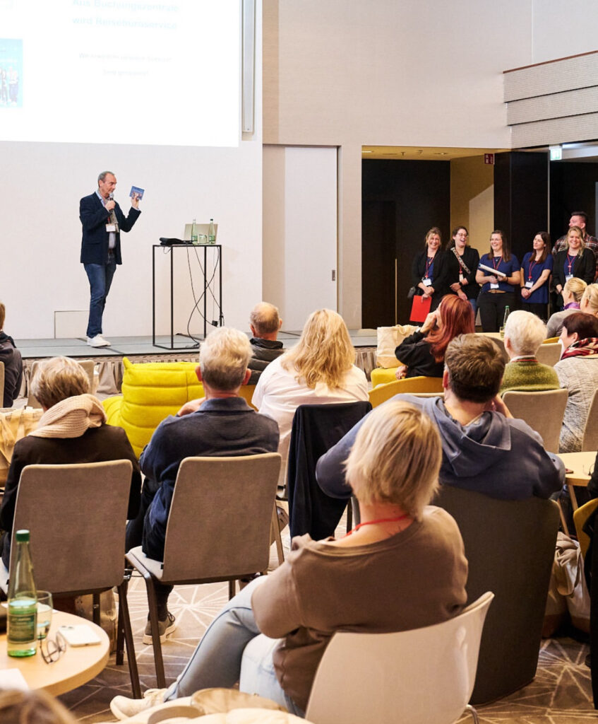 a man standing on a stage giving a presentation to a group of people