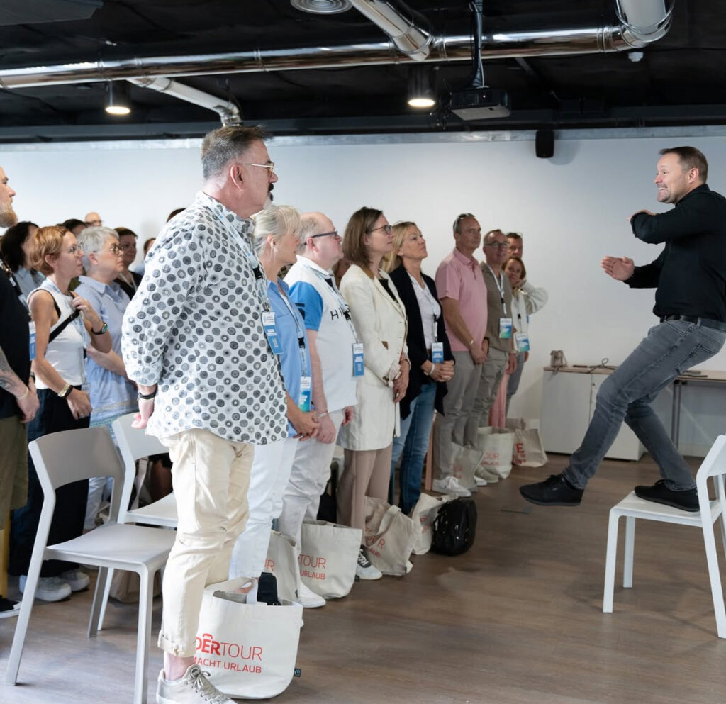 a man standing on a chair in front of a group of people